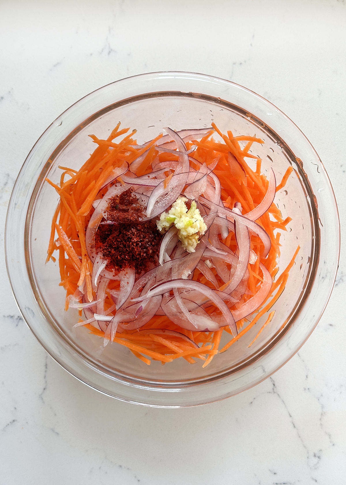 spicy carrot salad ingredients in glass mixing bowl