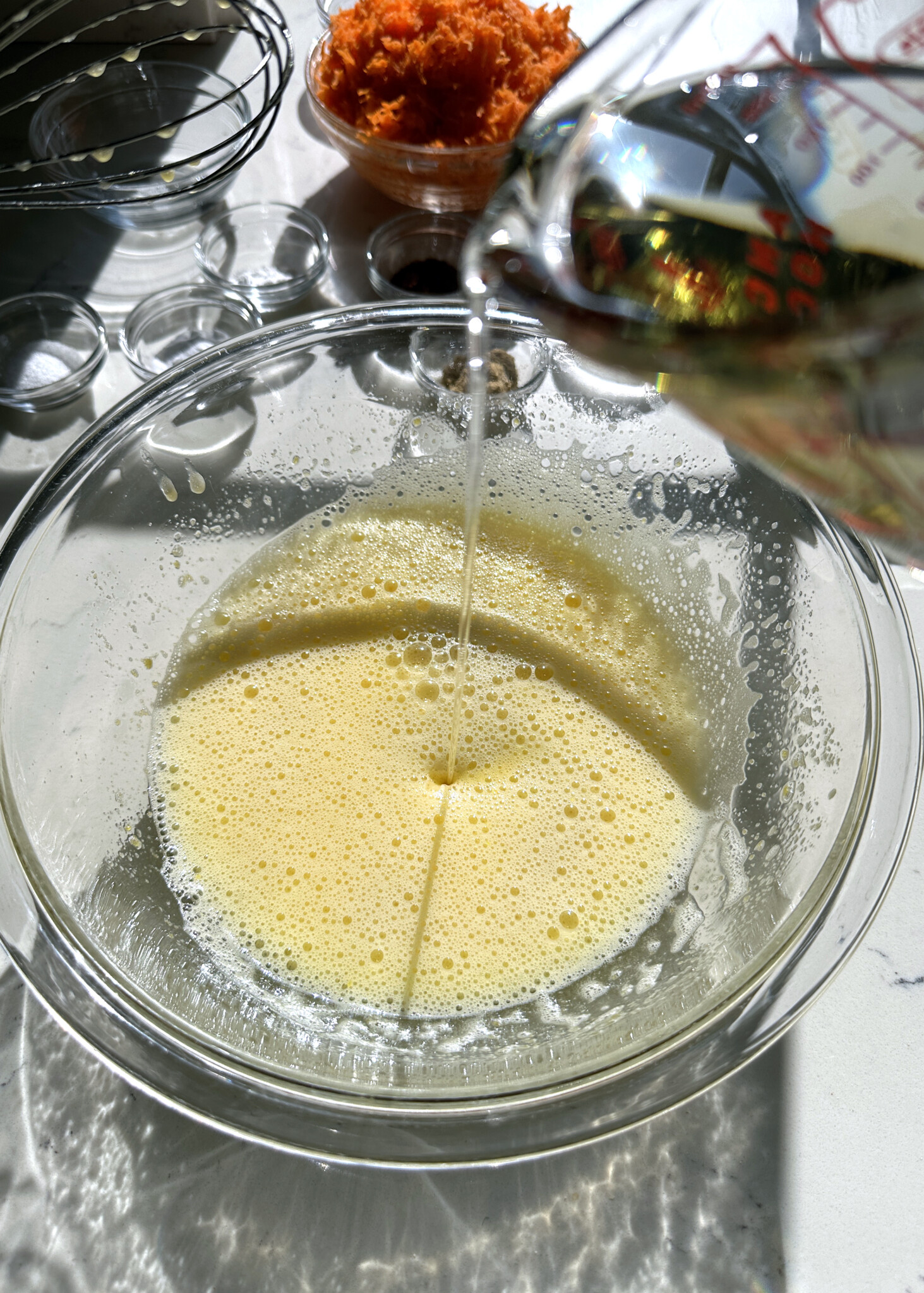 drizzling oil into cake batter in glass mixing bowl