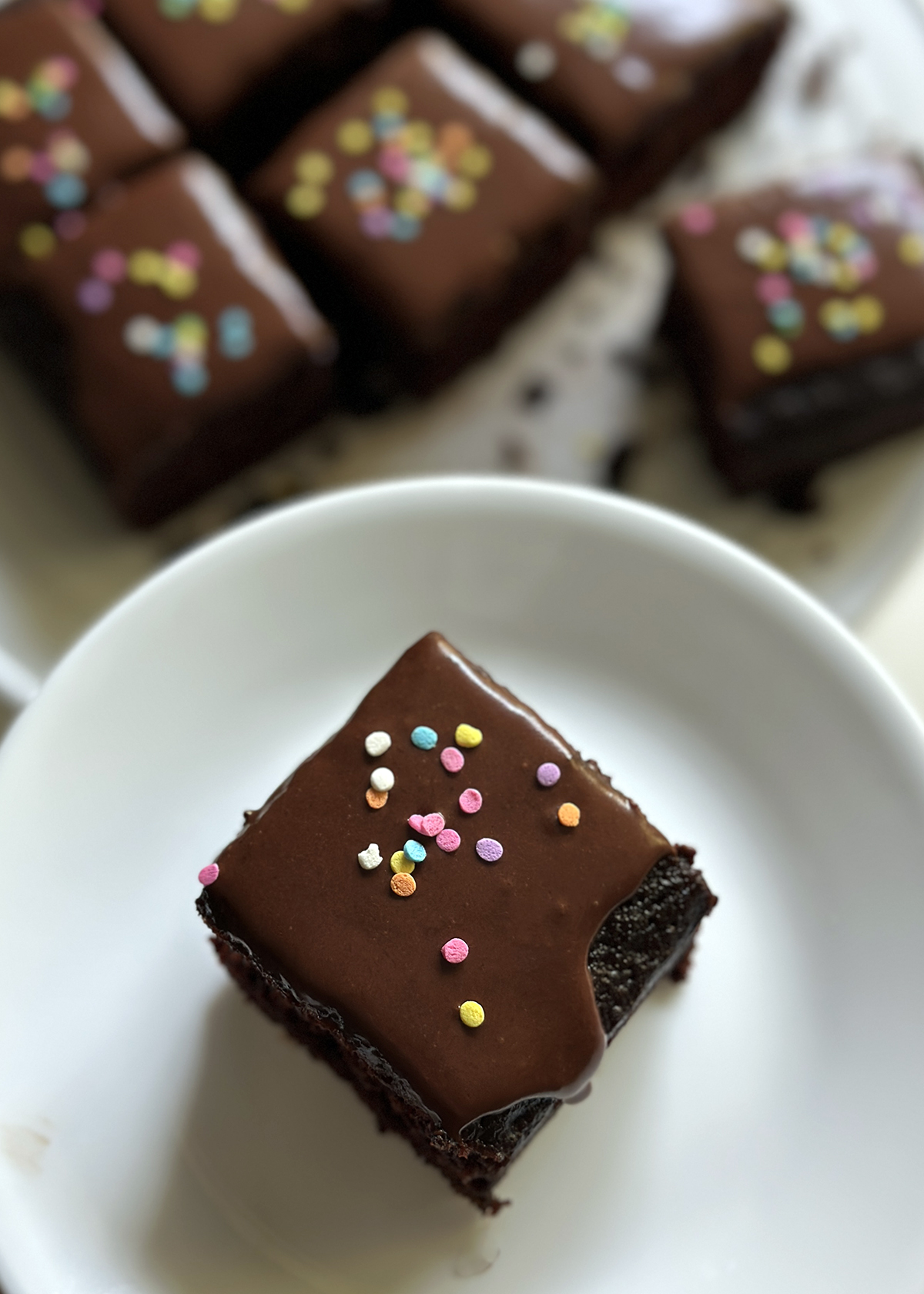 vegan iced chocolate cake piece on plate