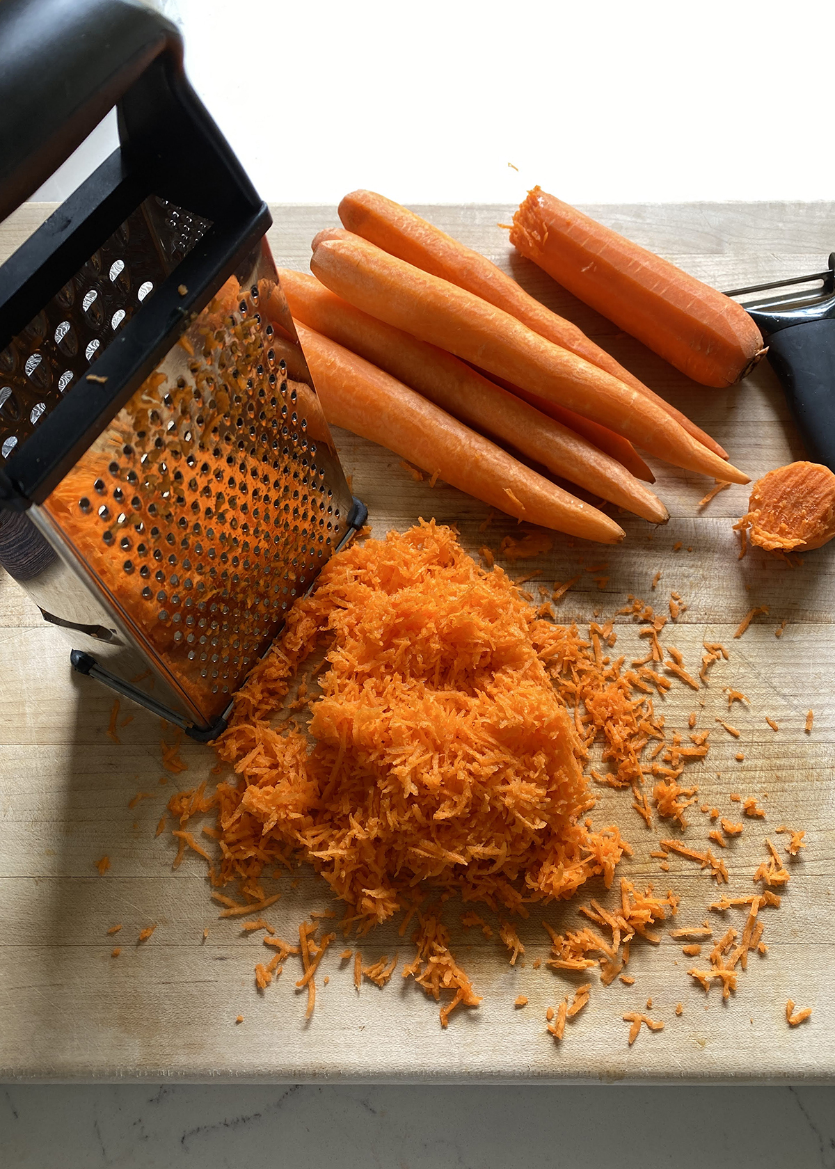 fine shredded carrots on cutting board with box grater