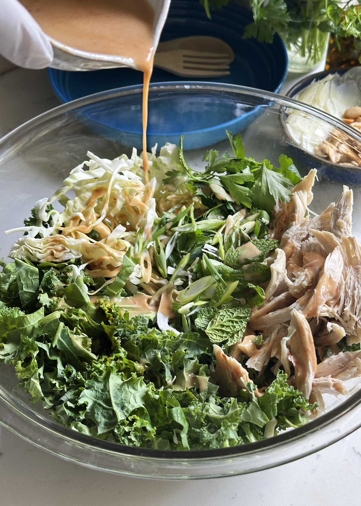 drizzling peanut vinaigrette on kale salad