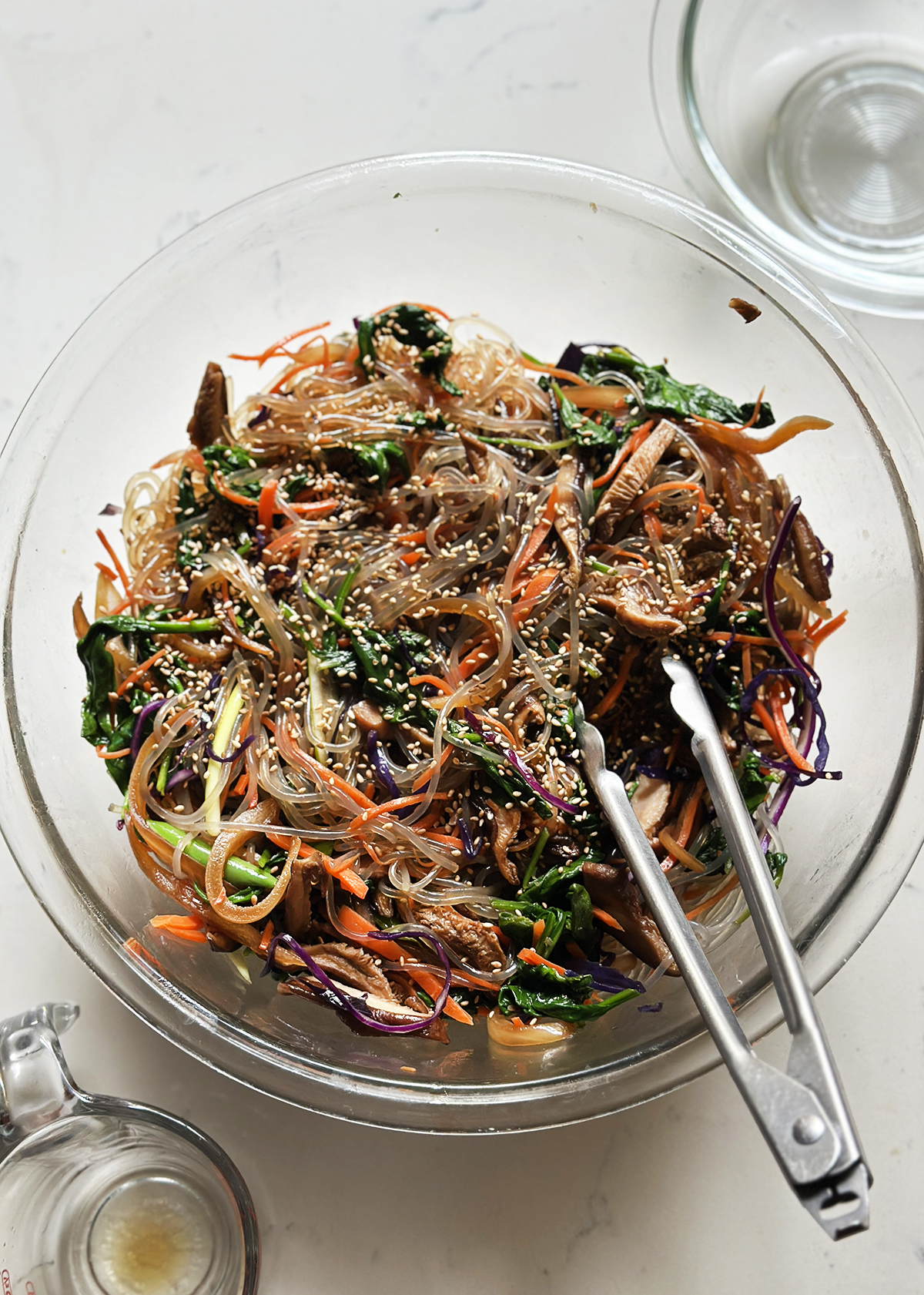 garnishing japchae with sesame seeds
