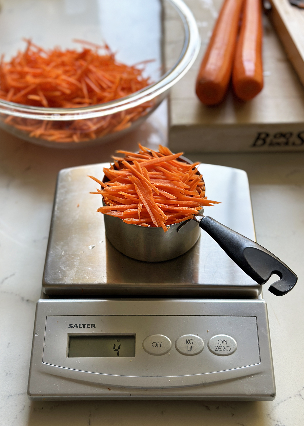 shredded carrots in measuring cup on digital scale
