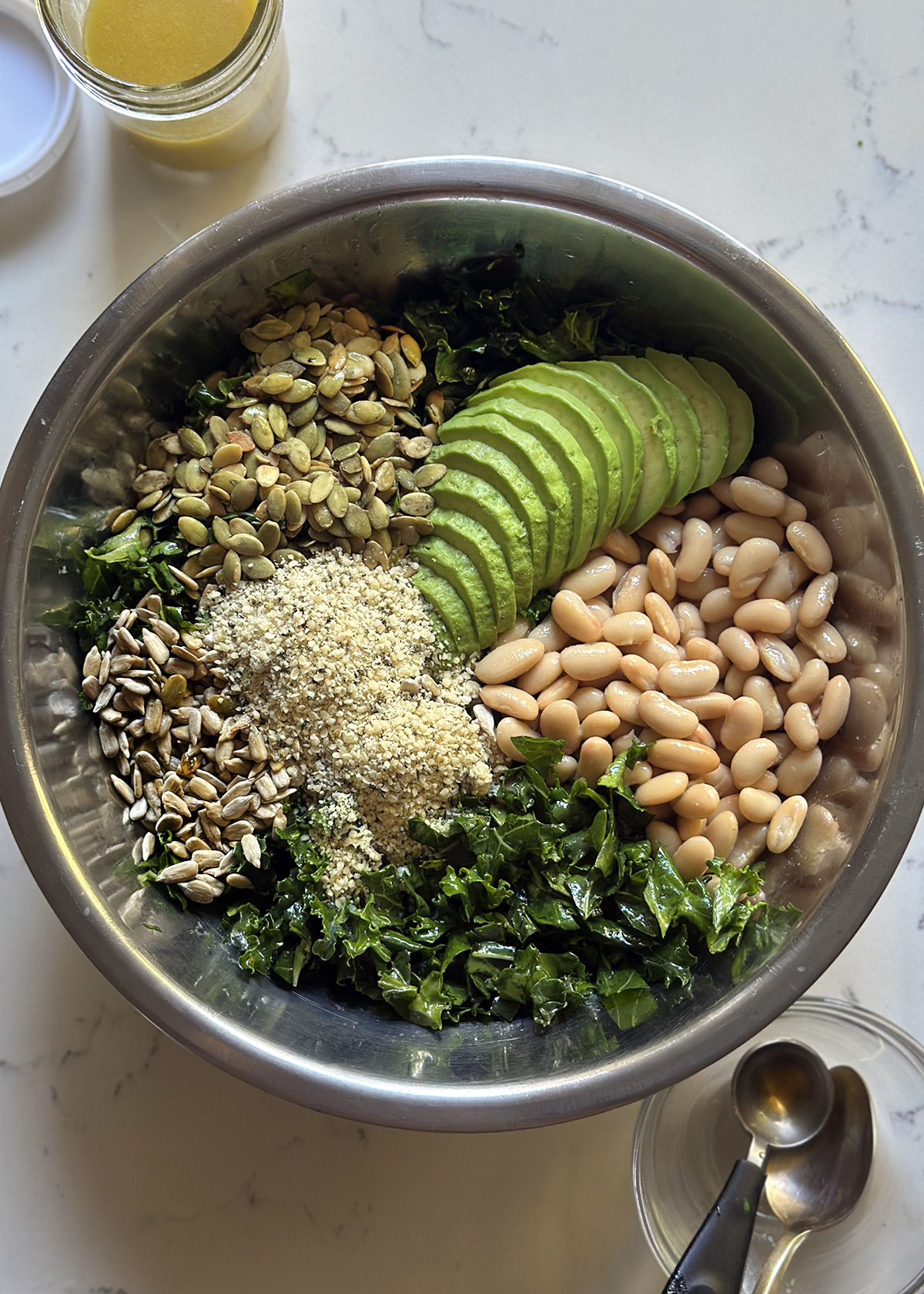 kale salad ingredients in stainless salad mixing bowl