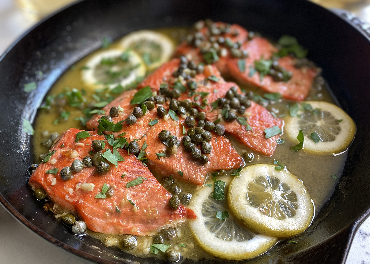 salmon piccata with lemon and capers in cast iron skillet